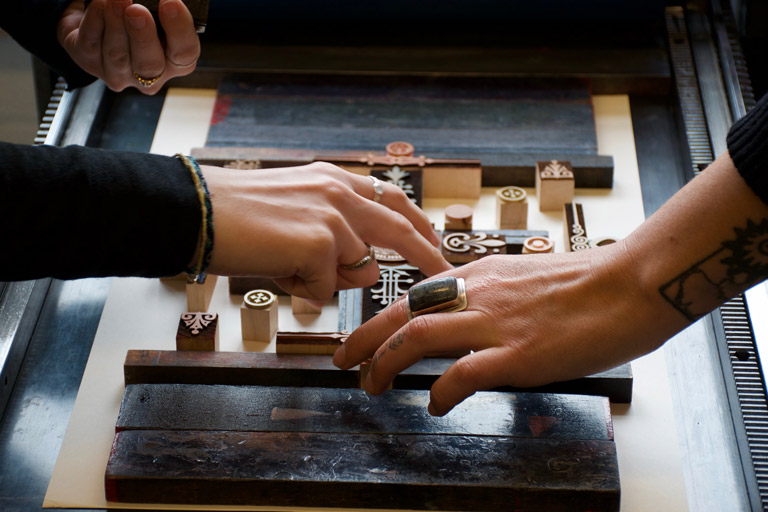 Two sets of hands working with wood type. 