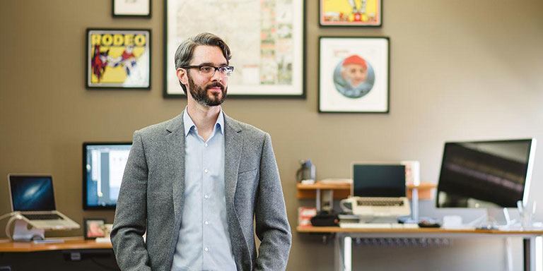 A person stands in front of a wall of art.