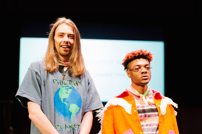 A student on a runway with a person modeling their work.