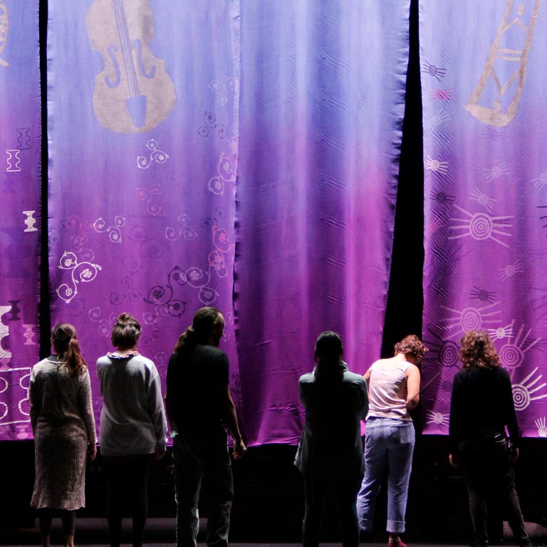 Students in front of a large purple tapestry.
