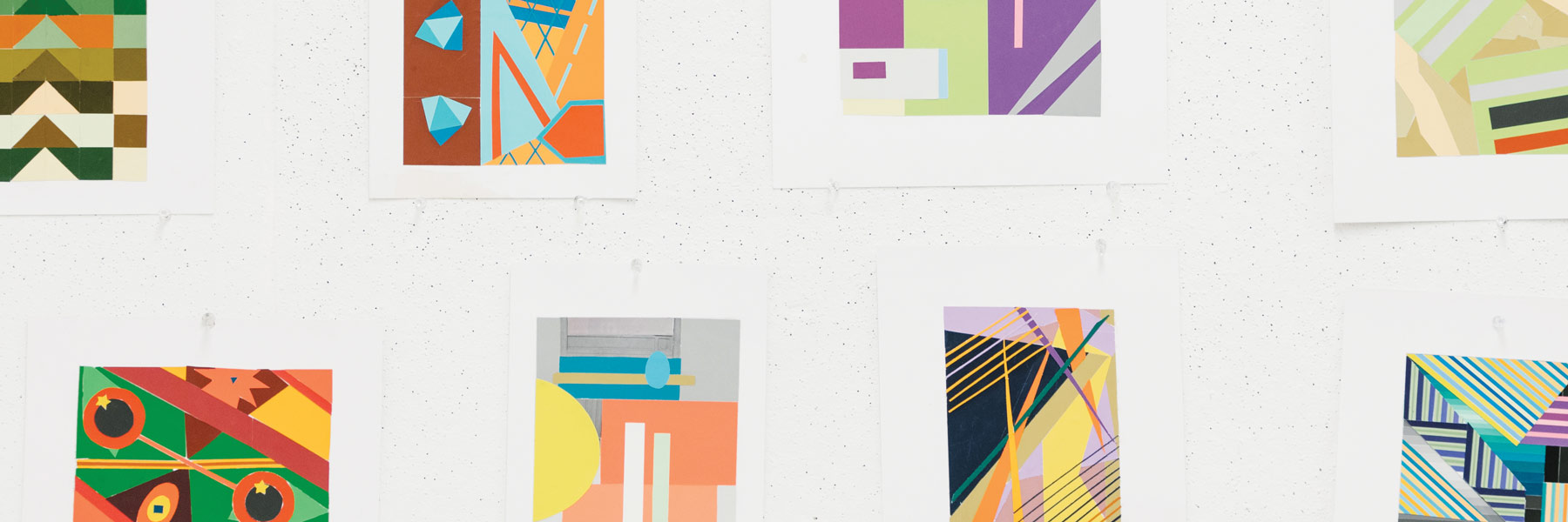 Paintings and drawings pinned to a wall.