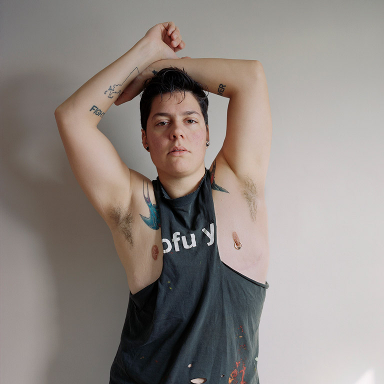 A person stands with arms over their head.