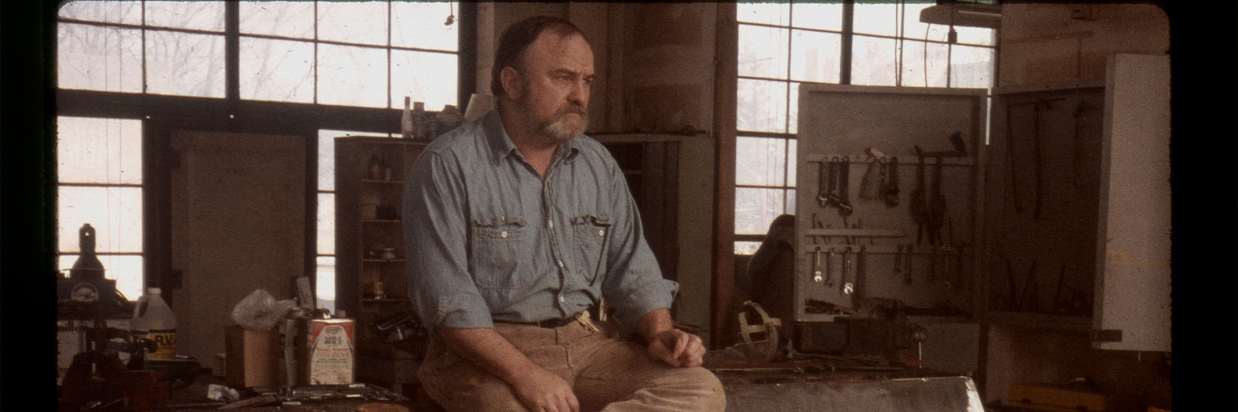 A man in his art studio looks off into the distance.