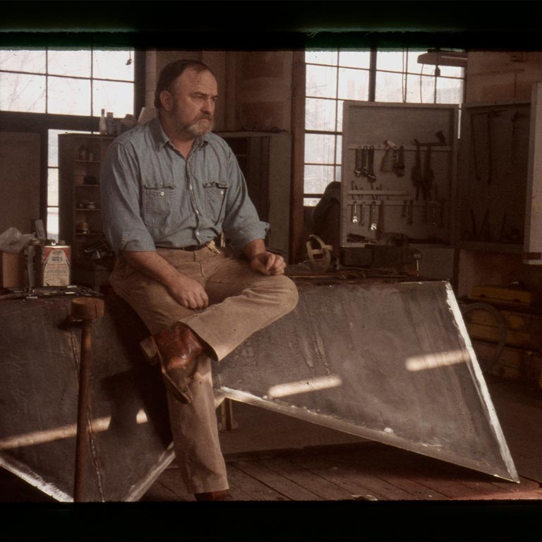 A man in his art studio looks off into the distance.