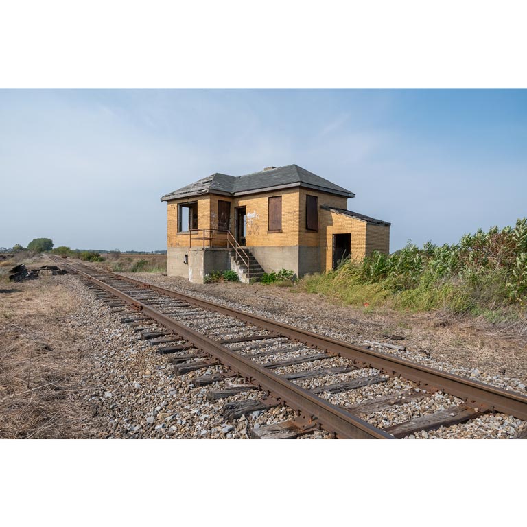 An abandoned brick building alongside a railroad.