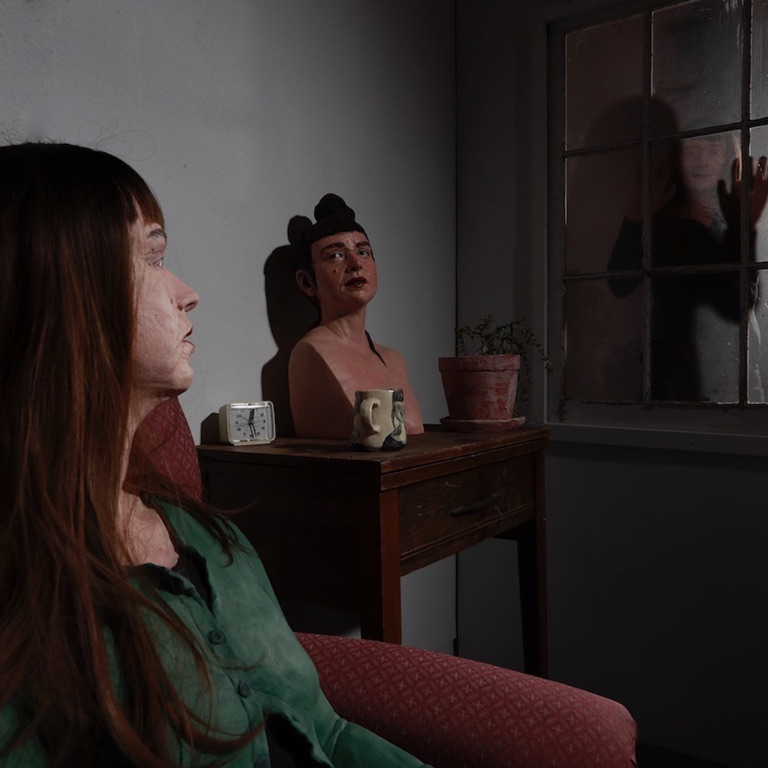 An ceramic installation of person-like forms that look like each other, looking at themselves. 