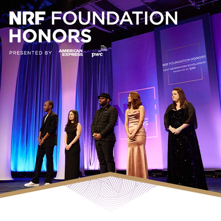 Five people dressed in nice clothing stand on a stage to receive awards.