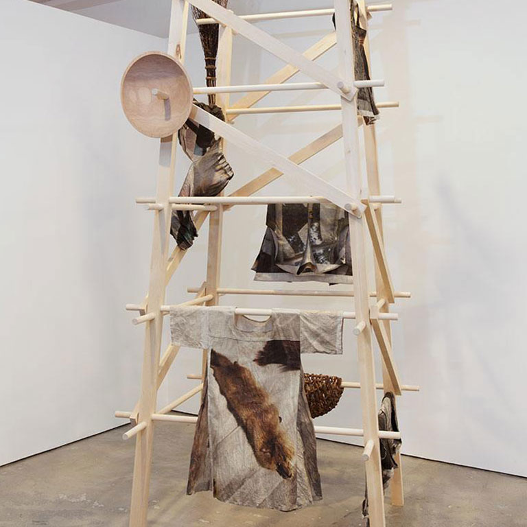 Scraps of clothing hang from a wooden display