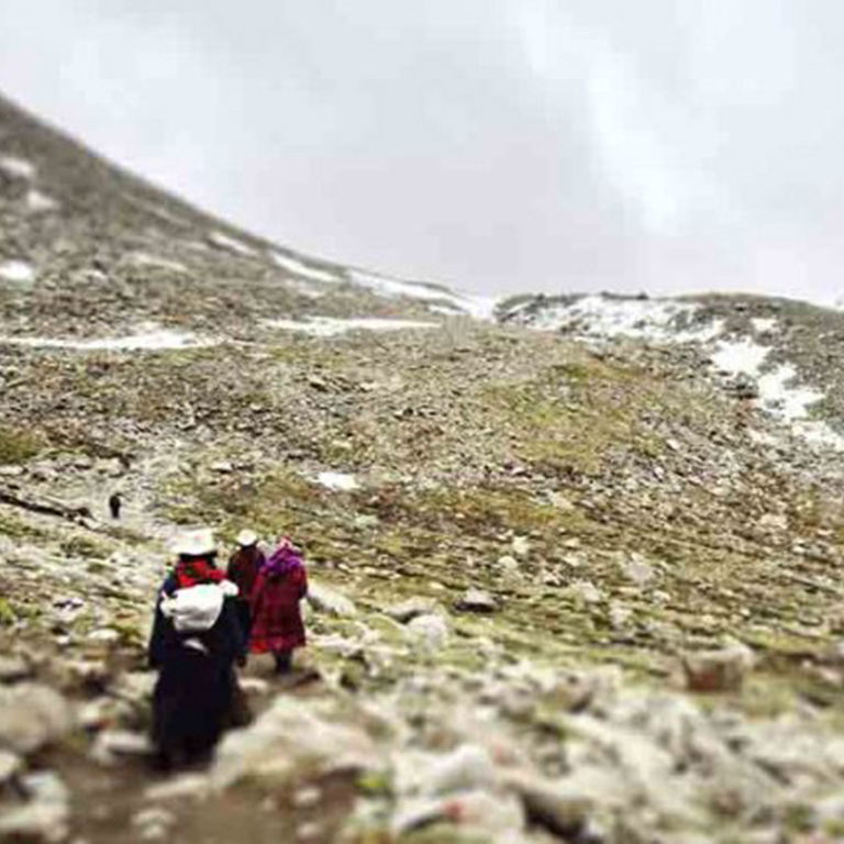 Three people walk across a snowy mountain.