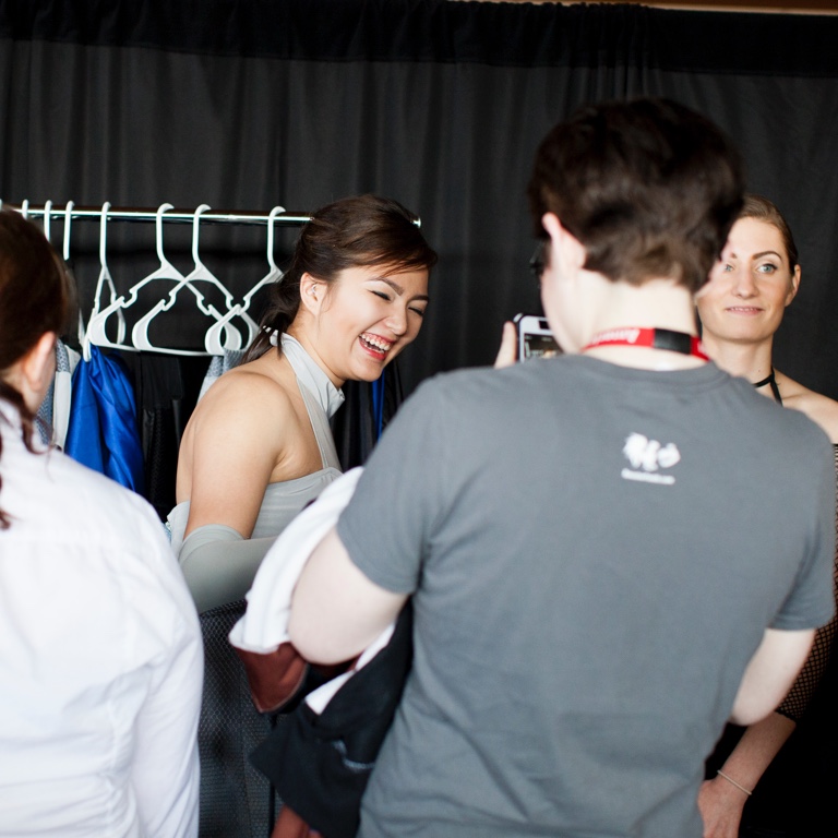 A group of people stand in front of a rack with hangers.