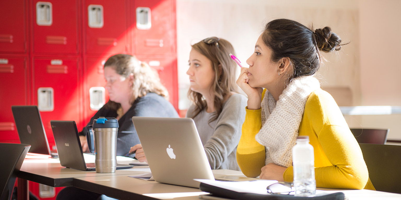 Three students engaged in a lecture.