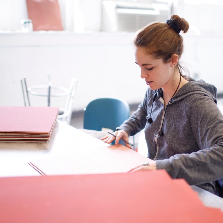 A person sits with large red pieces of cardboard.