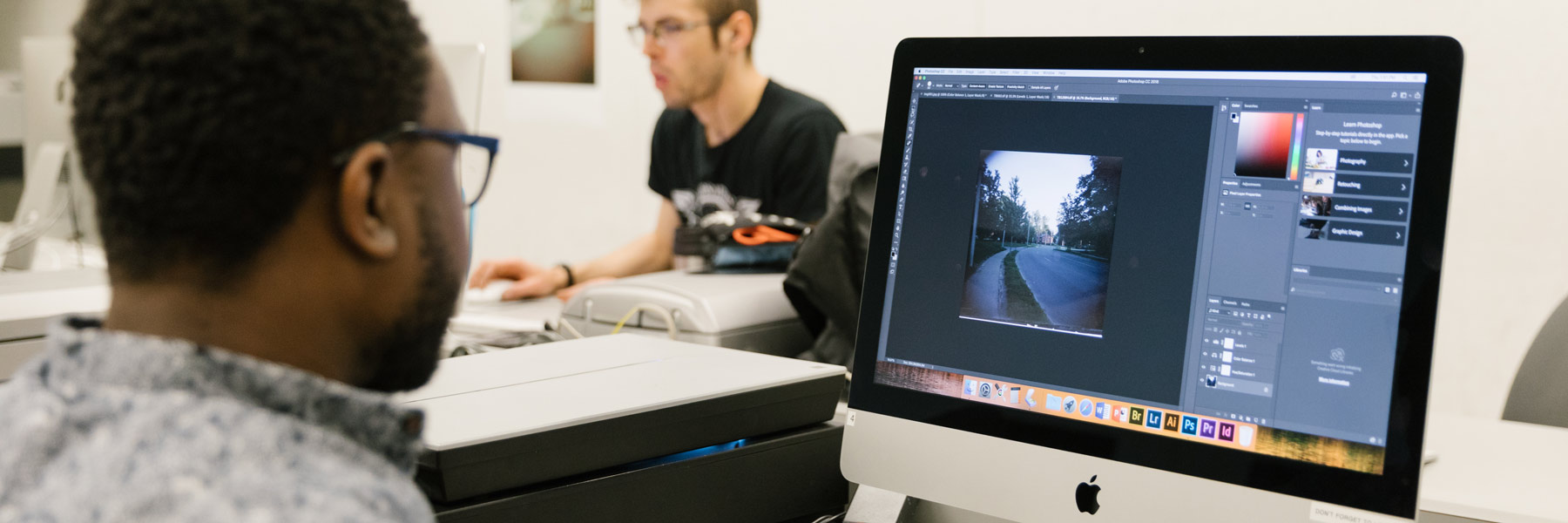 Two people work at desktop computers.